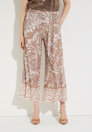 Hoch taillierte, weit geschnittene Hose mit braun-weißem tropischem Blatt- und Tiermuster, Taillenbindung, getragen mit braunen offenen High Heels.