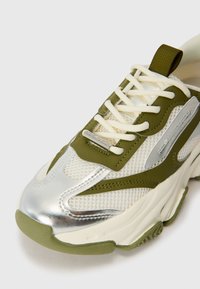 Grønne og hvide mesh-sneakers med metaliske sølv detaljer. Har tykk sål, snørebåndslukning og brandlogo på metalmærke.