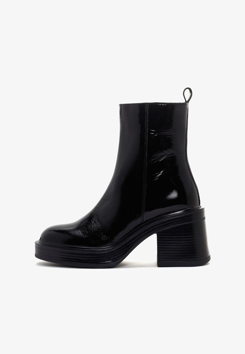 Bottine noire brillante à talon bloc épais avec une languette de traction à l'arrière, dotée d'une semelle épaisse et d'une texture supérieure lisse.
