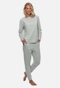 Grå loungewear sæt lavet af blødt materiale; indeholder en langærmet top og tætsiddende bukser med sidelommer, som giver en afslappet pasform.