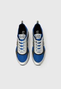 Kék és ezüst tornacipők hálós és szintetikus felsőrésszel, fűzős lezárással, húzófülekkel és kontrasztos fekete talppal.