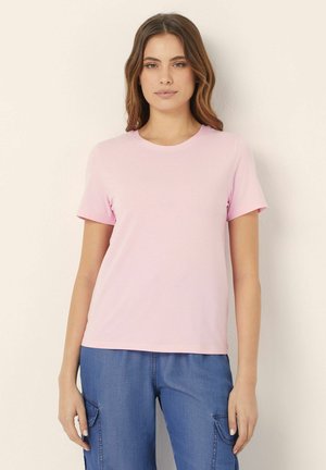 T-shirt rosa a maniche corte realizzata in tessuto leggero, con colletto girocollo e una vestibilità comoda. Indossata con pantaloni cargo blu.