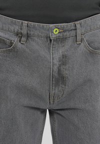 Grå denimjeans har en grøn knap og kontraststing, med fem-lommer design og en klassisk lige pasform.