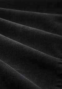 Crni materijal s mekanom, glatkom teksturom, s istaknutim naborima i uniformnom bojom, pogodan za razne tekstilne primjene.