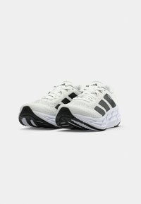 Witte sportschoenen met zwarte accenten, bovenkant van mesh, gevoerde zool en opvallend drie-stripes ontwerp aan de zijkanten.