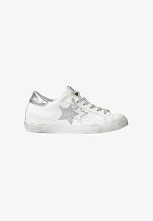 Scarpa da ginnastica bianca basse con disegni a stella argentati, linguetta del tallone argentata e lacci bianchi, con suola leggermente consumata.