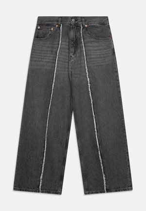 Szerokie czarne dżinsy z frędzlami na szwie środkowym, zniszczoną fakturą, metalowymi guzikami i tradycyjnym pięciopocketowym wzorem.