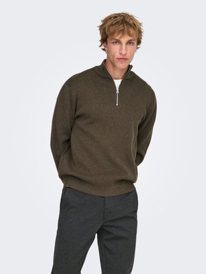 Pull vert foncé à fermeture éclair avec col montant, fabriqué en tissu texturé. Porté avec un pantalon gris, doté d'une coupe décontractée et de poignets côtelés.