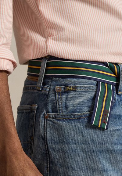 Πολύχρωμη ριγέ υφασμάτινη ζώνη με πράσινες, κίτρινες και μπλε ρίγες, φορεμένη με ανοιχτόχρωμο τζιν με ετικέτα λογότυπου «Polo».