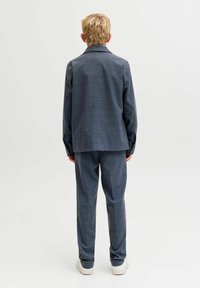 Szürke kockás öltöny, laza szabással, egysoros zakóval és hozzá illő nadrággal. Puha textúra és minimalista dizájn.