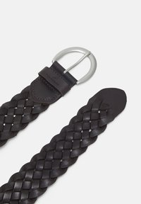 Cinturón de cuero trenzado en marrón oscuro con hebilla de metal plateado, que presenta una textura suave y acentos cosidos. Etiqueta de la marca visible en el cuero.