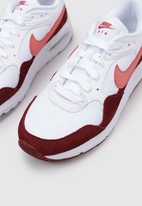 Nike Air Sneaker mit einem weißen Obermaterial aus Canvas, burgunderfarbenen Wildleder-Akzenten und einem rosa Logo, runder Zehenpartie und Schnürverschluss.
