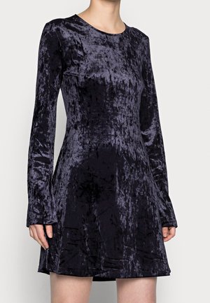 Langärmliges Samtkleid in Dunkellila mit Rundhalsausschnitt, tailliertem Oberteil und schwingendem Rock, der eine weiche, strukturierte Oberfläche aufweist.