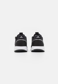 Zapatillas deportivas negras con parte superior de tela de malla, collar acolchado y entresuela blanca. Presentan sutiles acentos de logo y suela de goma texturizada.