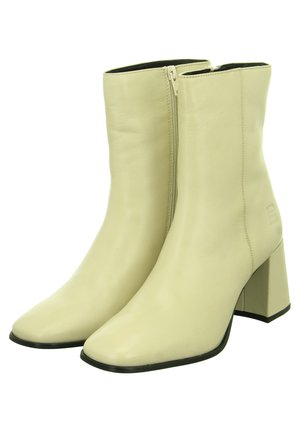 Botines de cuero beige con punta puntiaguda, cremallera lateral y tacón cuadrado grueso. Textura suave con detalles mínimos de costura.