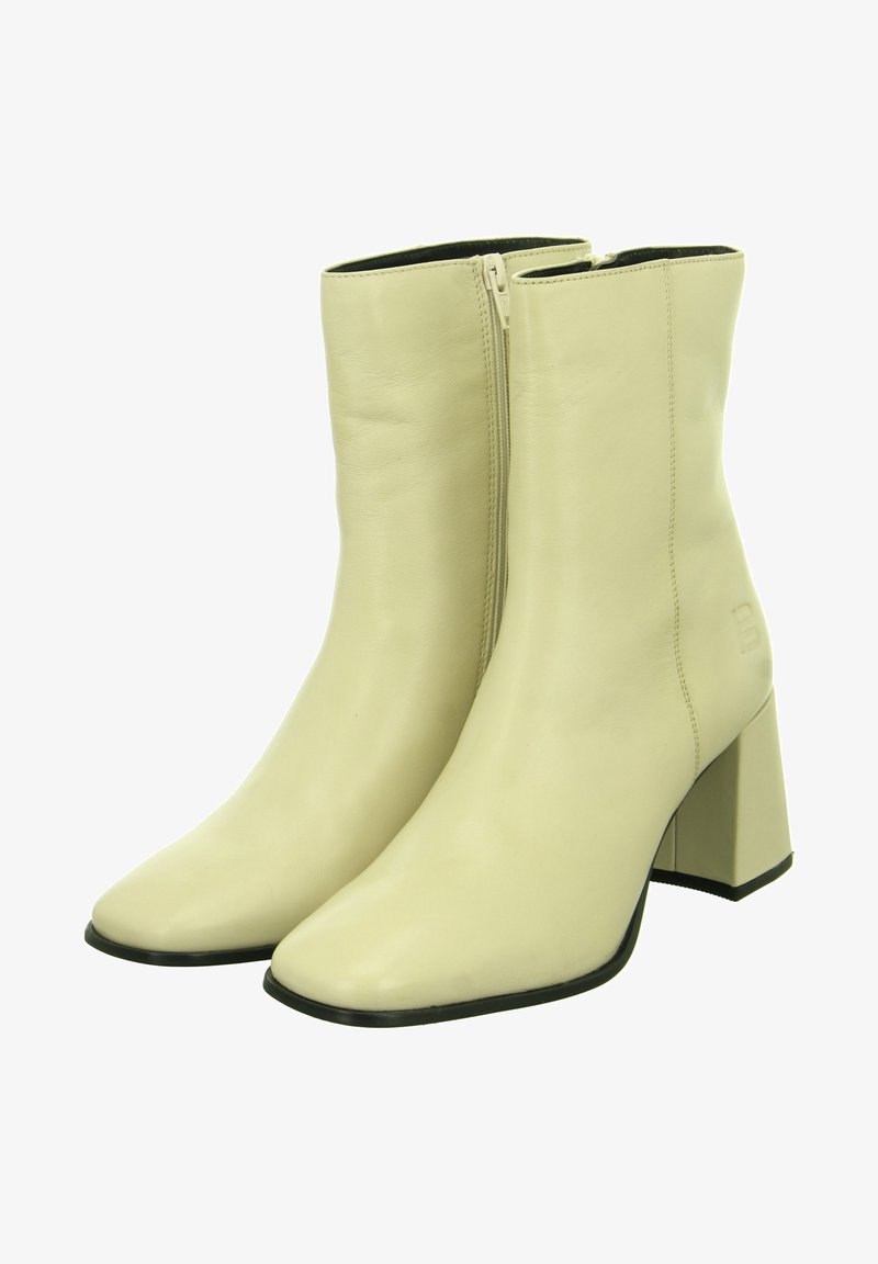 Bottes chevilles en cuir beige avec un bout pointu, une fermeture éclair latérale et un talon carré épais. Texture lisse avec un minimum de couture.