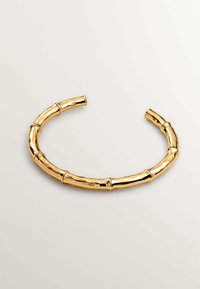 Pulsera de puño color oro diseñada para asemejarse al bambú, con una textura suave y pulida y bordes redondeados, presentando secciones segmentadas parecidas al bambú.