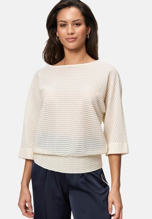 Pull en tricot couleur crème avec un motif de vagues texturé, encolure large, manches trois-quarts et coupe décontractée.