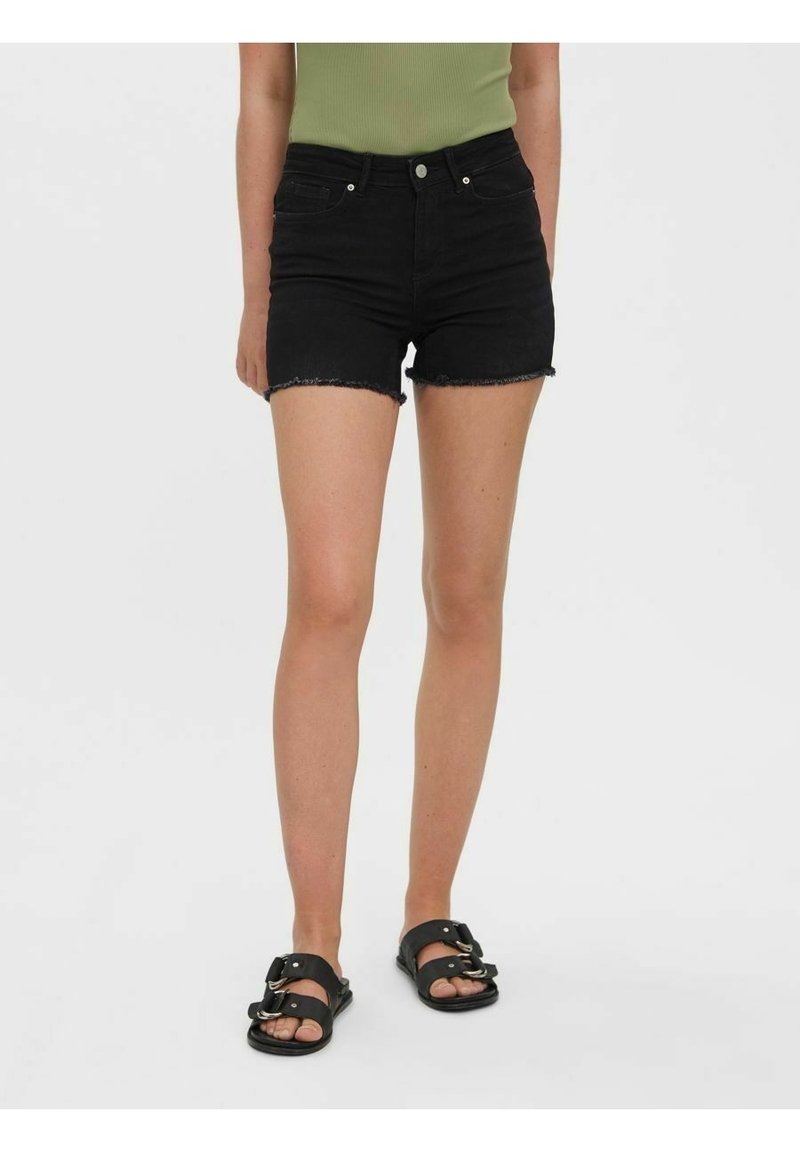 Svarta denimshorts med fransad fåll, högmidjad design och femficksstil, ihop med svarta sandaler.