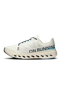 Fehér, könnyű futócipő hálós felsőrészsel, fekete fűzőkkel, feltűnő "ON RUNNING" felirattal, és vastag, párnázott talppal, amelyen kivágások találhatók.