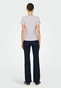 Stribet t-shirt i lys lilla og hvid, parret med mørke flared jeans. Skjorten har korte ærmer og rund halsudskæring.
