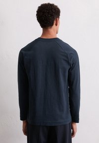 Heren overhemd met lange mouwen in donker marineblauw. Kenmerken zijn een ronde hals, raglanmouwen en een zachte, gestructureerde stof met eenRelaxte pasvorm.