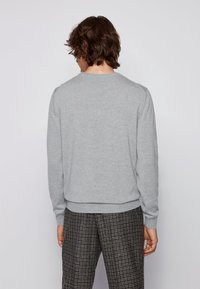 Grau Sweatshirt mit rundem Halsausschnitt, langen Ärmeln und geripptem Saum, aus einem weichen, strukturierten Stoff gefertigt und mit einer taillierten Silhouette.