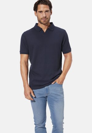 Marineblaues Polohemd mit Kragen, kurzen Ärmeln und einem strukturierten Stoff. Kombiniert mit hellblauen Jeans, die einen lässigen Fit zeigen.