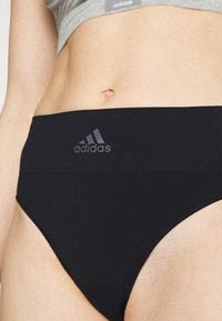 Fekete, magas derekú alsónadrág sima anyagból, sötétszürke, diszkrét Adidas logóval a derékon.