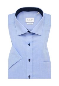 Camicetta azzurro chiaro con chiusura a bottoni, realizzata in tessuto dalla texture liscia. Presenta un colletto interno a pois blu navy, taschino sul petto e maniche corte.