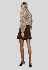 Blusa beige trasparente con stampa pitone, maniche a volant e legatura sul retro. Abbina a una gonna marrone scuro e tacchi neri, creando una silhouette adatta.