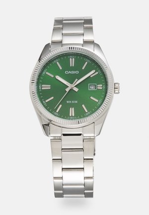 Montre-bracelet Casio en métal argenté avec cadran vert, index horaires argentés, trois aiguilles, affichage de la date à 3 heures et bracelet à maillons métalliques.