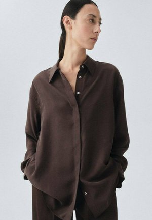 Brown silk button-up shirt with a pointed collar, long sleeves, and a relaxed fit. Details include small white buttons and a smooth texture.