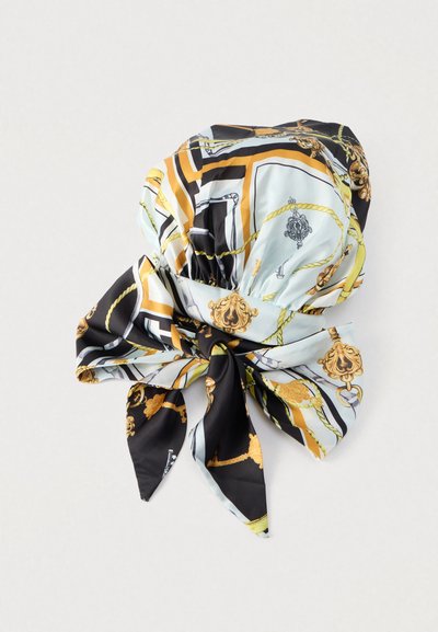 Μεταξωτό φουλάρι με ανοιχτό γαλάζιο φόντο και σχέδια σε μαύρο, χρυσό και κίτρινο, που περιλαμβάνουν σκοινιά και περίτεχνα μετάλλια, δεμένο σε φιόγκο.