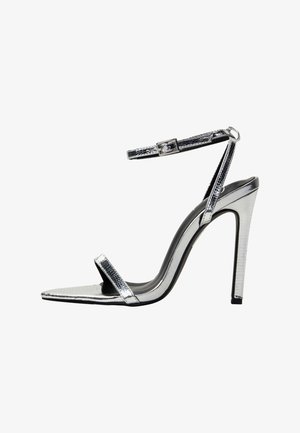 Srebrne metaliczne sandały na wysokim obcasie z ostrym noskiem, cienkim paskiem na kostkę, gładką teksturą i eleganckim błyszczącym wykończeniem.