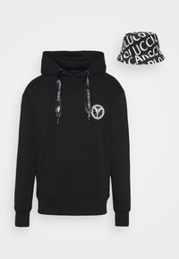 Sweat à capuche noir avec poche avant, cordons de serrage à logo, logo circulaire blanc sur la poitrine, assorti à un bob noir recouvert d'un motif de texte blanc.
