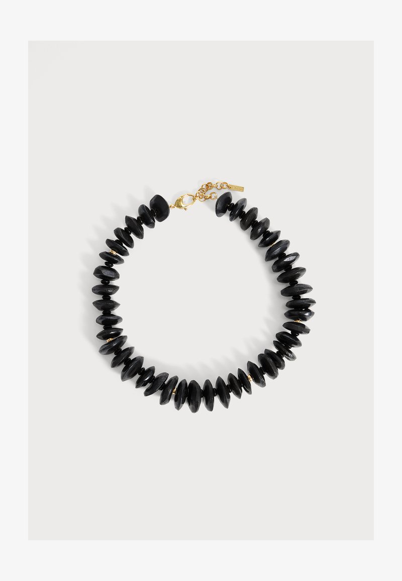 Collier avec des perles noires mates en forme de disque et de petites perles intercalaires dorées, fermé par un fermoir mousqueton doré et une chaîne réglable.