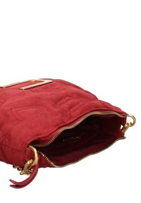 Borsa a tracolla in suede rosso con hardware dorato. Presenta una texture trapuntata e una chiusura a zip sulla parte superiore. L'interno è foderato in tessuto rosso.