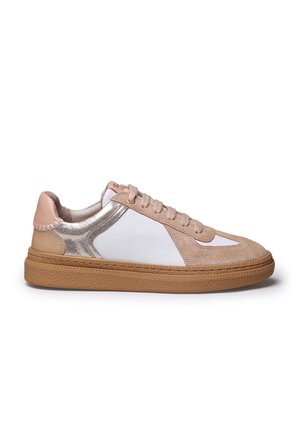 Low-top sneaker met beige suède, witte leren panelen, metallic zilveren accenten, tan rubberen zool en beige veters, zijaanzicht op witte achtergrond.