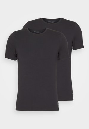 Deux t-shirts noirs à col rond avec des manches courtes, en tissu lisse. Chacun présente un logo discret sur le côté inférieur.