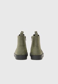 Botas de tobillo verdes con una textura suave, costuras reforzadas, suelas de goma negra y cremalleras traseras para facilitar el uso. Presenta un diseño de longitud hasta el tobillo.