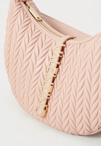Ροζ δερμάτινη τσάντα με υφή πλεξούδας, χρυσές λεπτομέρειες, κλείσιμο με φερμουάρ και έντονη λεπτομέρεια λογότυπου στο πλάι.