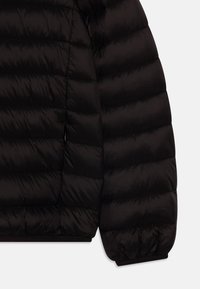 Chaqueta acolchada negra con un diseño acolchado, que presenta un acabado de nailon suave, puños elásticos y bolsillos con cremallera ocultos.