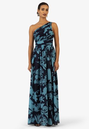 Eén-schouder maxi jurk in marineblauw met teal bloemenprint. Gepofte bodice, vloeiende rok en een soepel stoffen textuur. Kenmerkt een taille met riem.