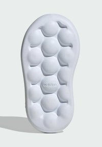 Adidas shoe sole in white with a textured honeycomb pattern, featuring raised circular bumps for cushioning and comfort.