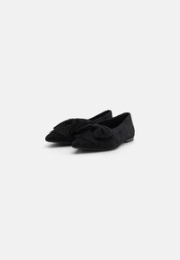 Balerini negri din suede, cu vârf ascuțit, prezentând un detaliu mare sub formă de fundă în partea din față și un toc joasă, plat. Textură fină pe întreaga suprafață.