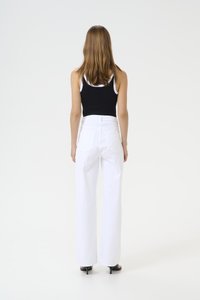 Pantaloni bianchi a gamba larga con vita alta, abbinati a una canotta nera. Presentano un design semplice, un tessuto morbido e dettagli di cucitura minimi.