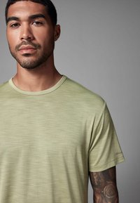Lys grøn kortærmet t-shirt med en tekstureret stof, rund halsudskæring og subtile syninger på ærmerne.