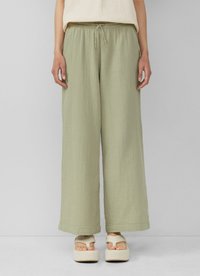 Lichtgroene, wijde broek van textuurstof met een elastische tailleband en trekkoord. Gecombineerd met plateausandalen.