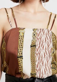 Camisola in satin marrone e crema con diversi motivi, tra cui stampa animalier e un design geometrico, con spalline sottili.